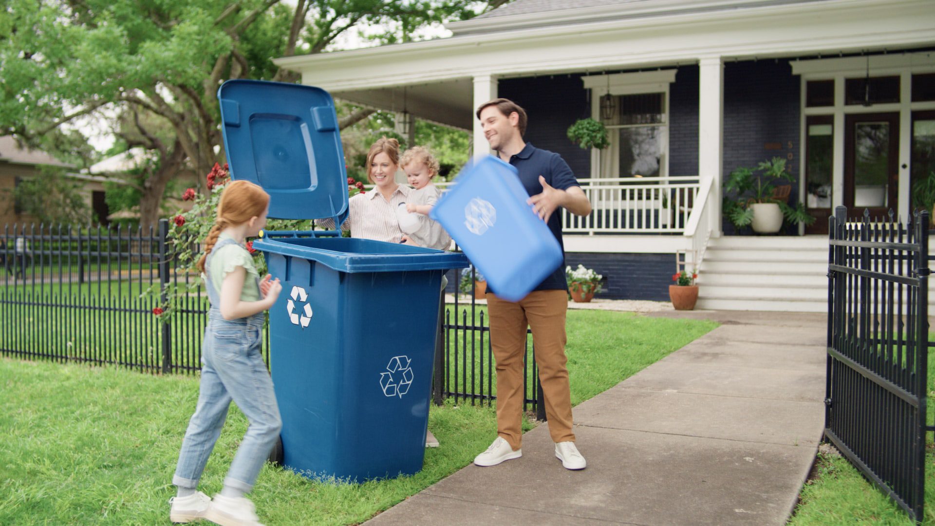 A family standing around a the recycling bin and adding to