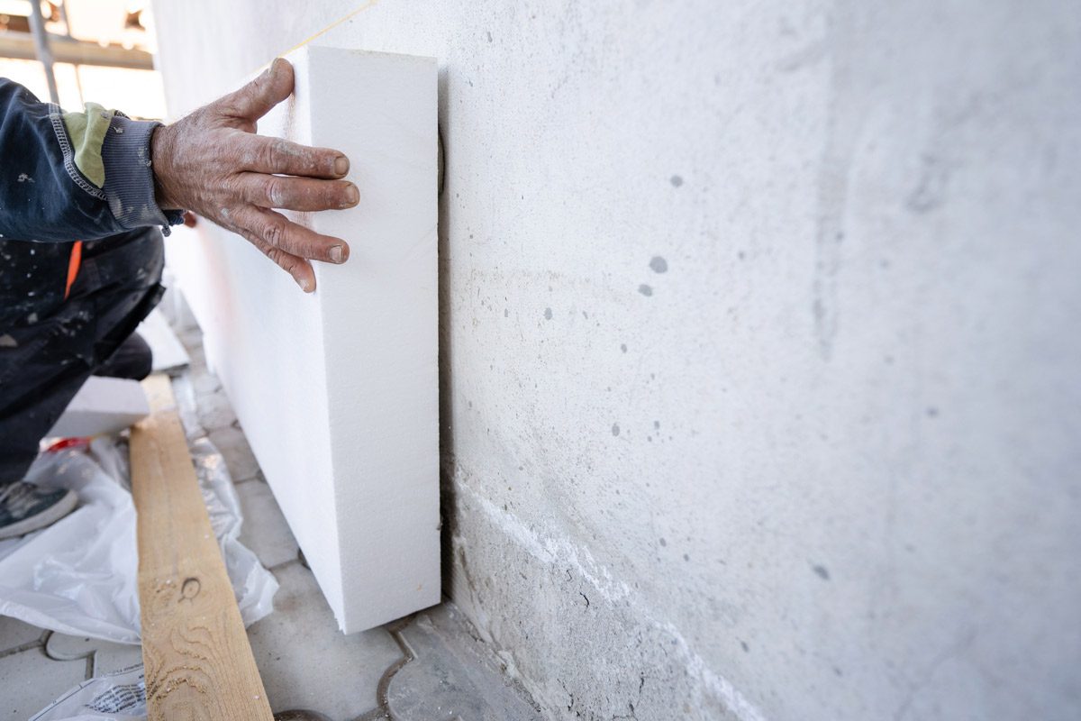 Worker Placing Sheet Insulation to Wall