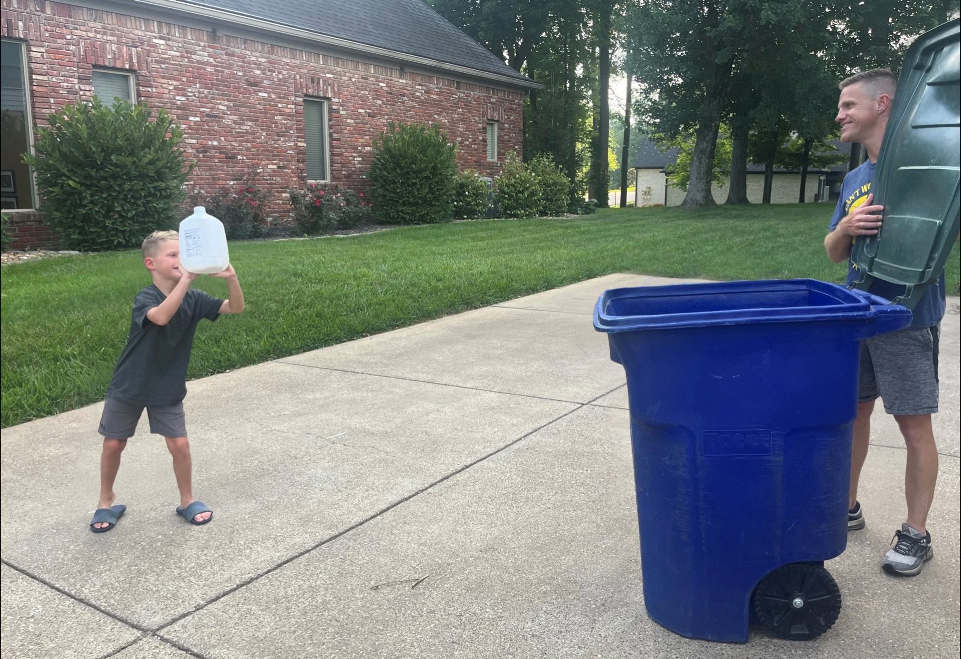 little boy throwing a milk jug into a recycling bin.