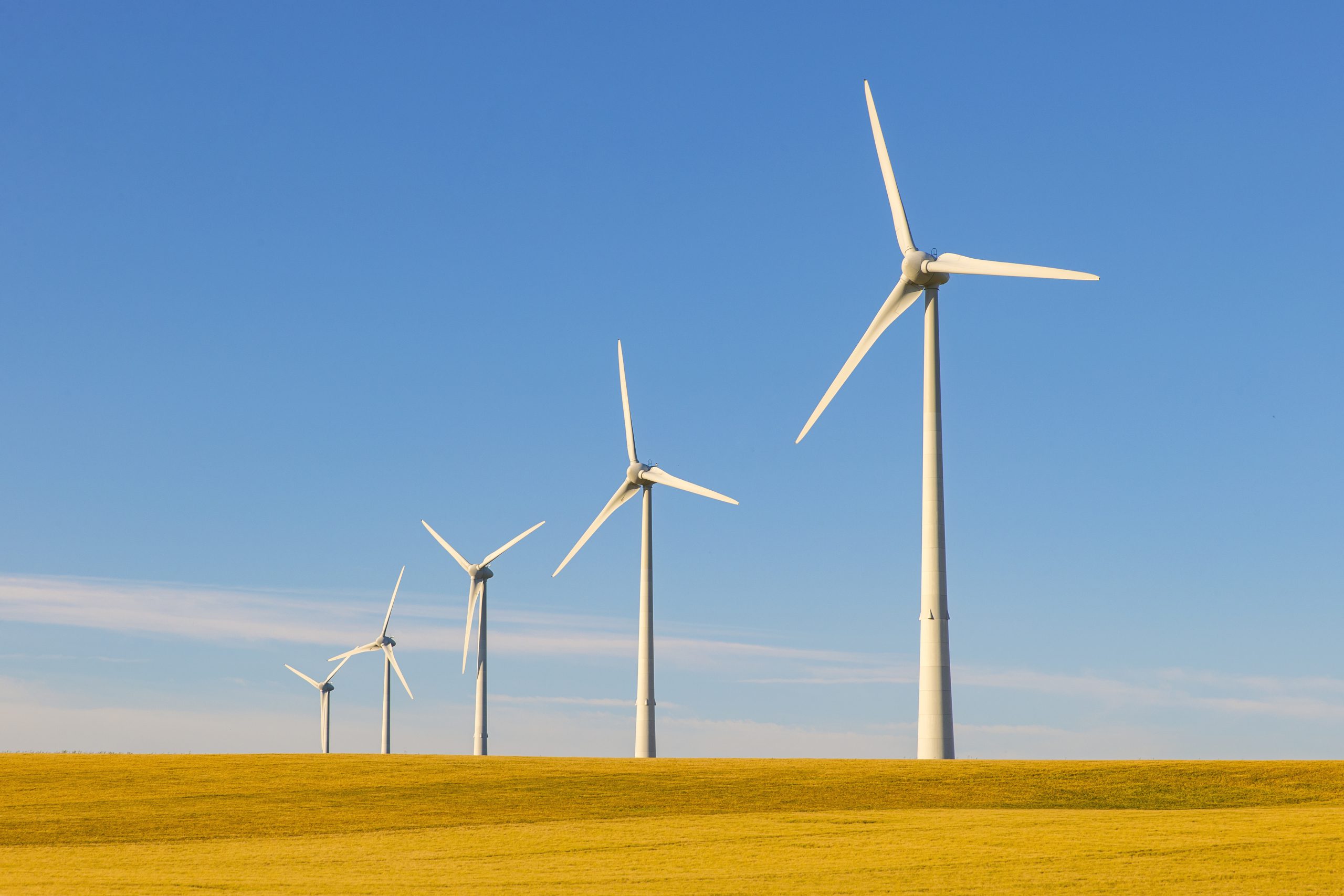 A row of wind turbines in desert.