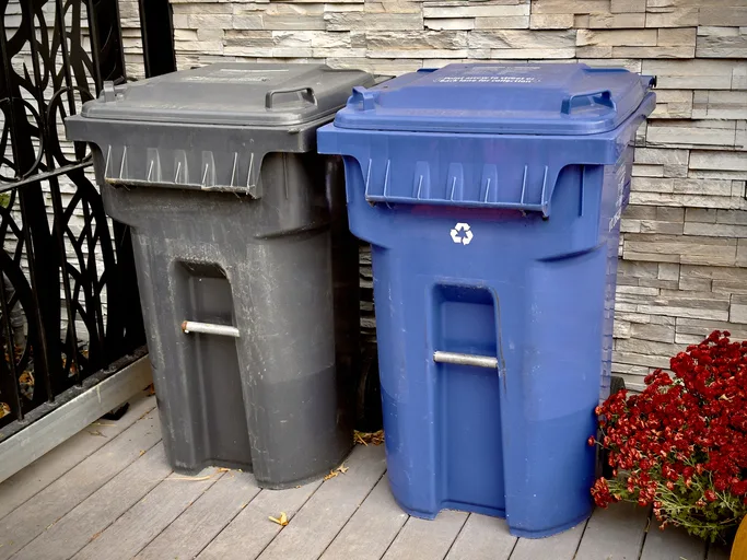 Blue and grey trash bins for waste separation near the house
