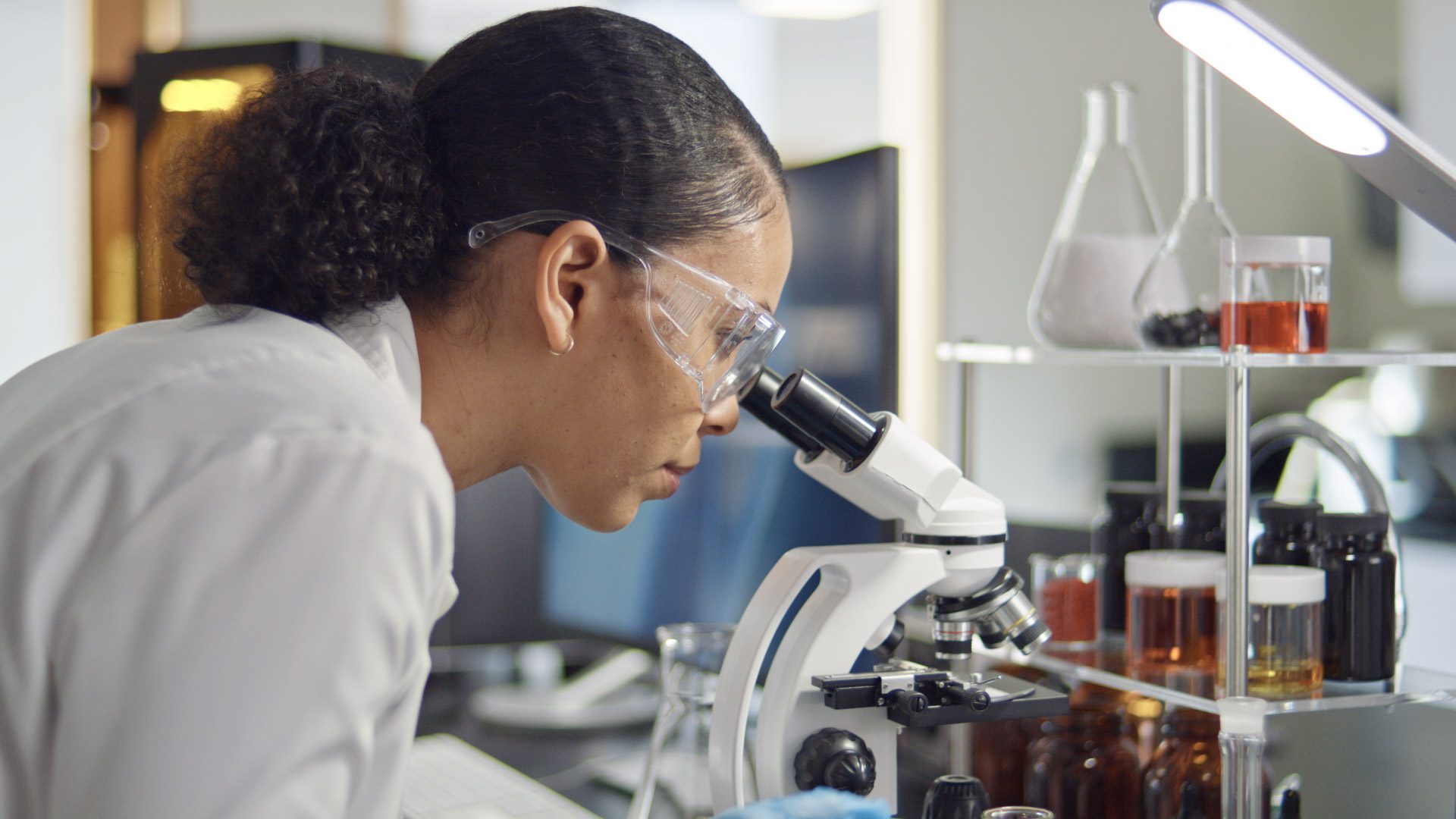 Female scientist looking into a microscope.