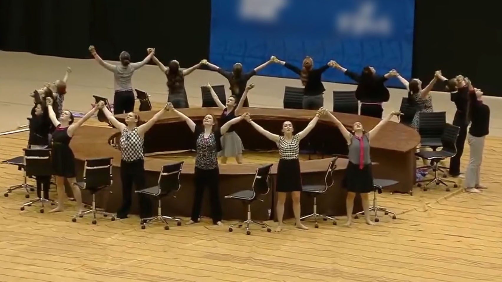 Members of winterguard hold raised hands around a circular table