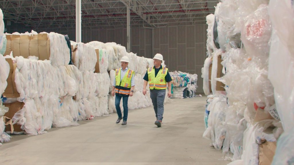 two men walking in a warehouse by plastic wrapping